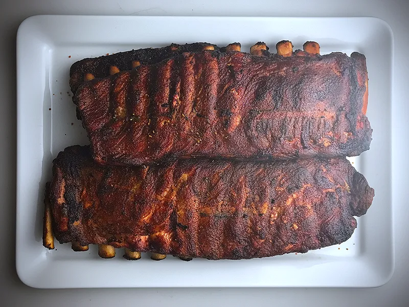 Two racks of Memphis dry-rub ribs on a white platter